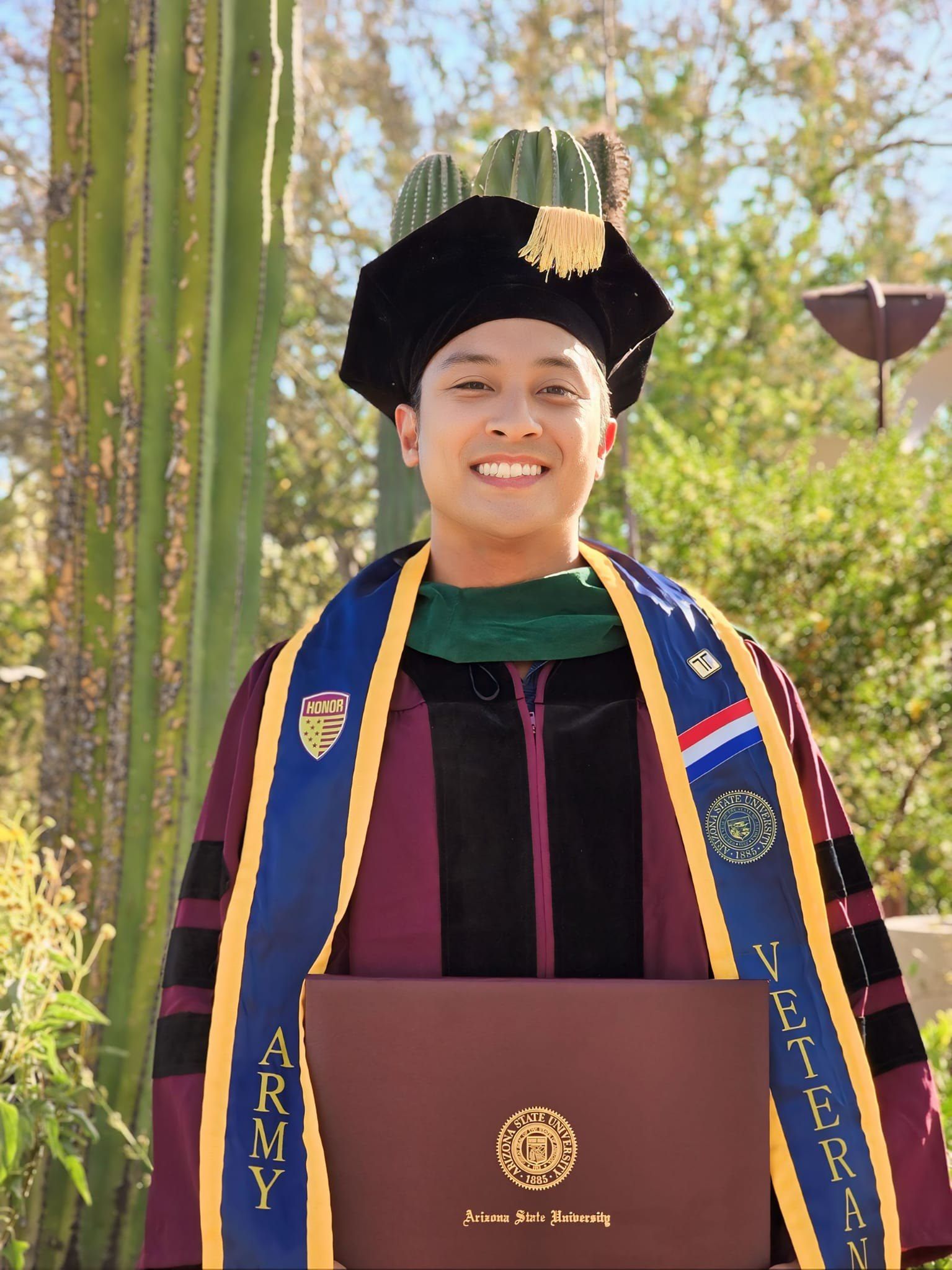 Jonathan Lu in doctoral regalia holding his Arizona State University diploma