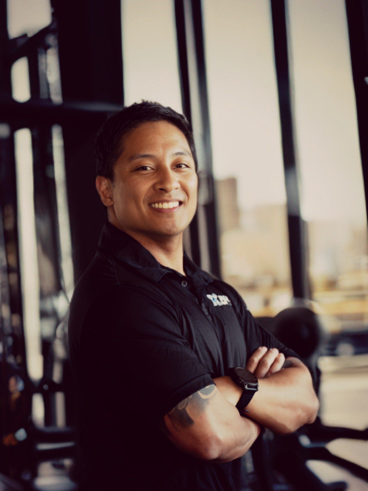 Jonathan Lu smiling with his arms folded in a gym